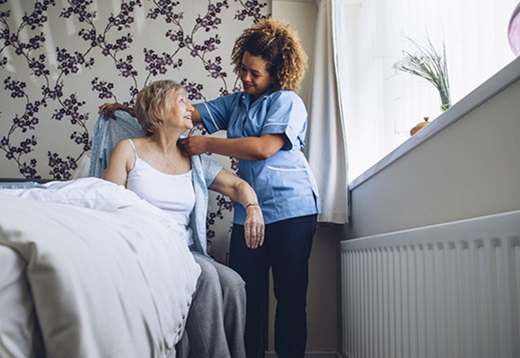 Home health aide assisting a patient with personal care at home